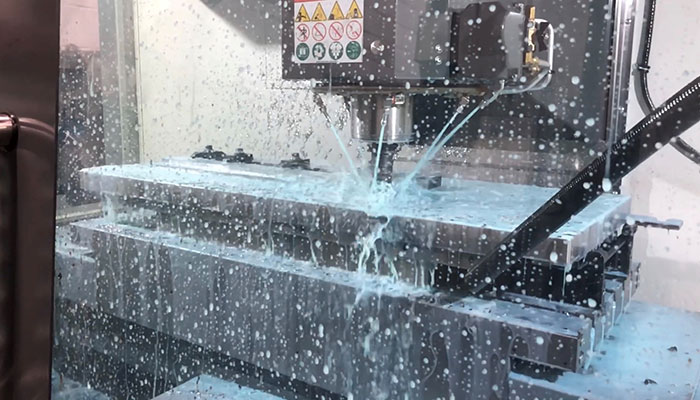 CNC machine coolant spray on parts being machined on a Midaco Automatic Pallet Changer pallet inside a vertical machining center.