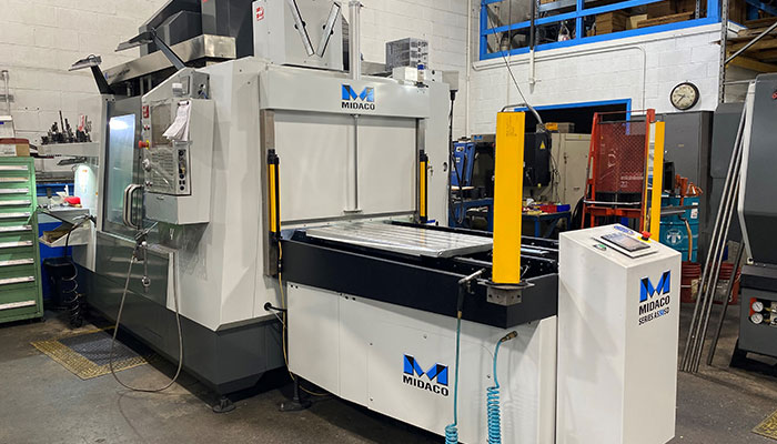 MIDACO Automatic Pallet Changer with yellow CE Light Curtain sensors mounted to a vertical machining center in a machine shop.